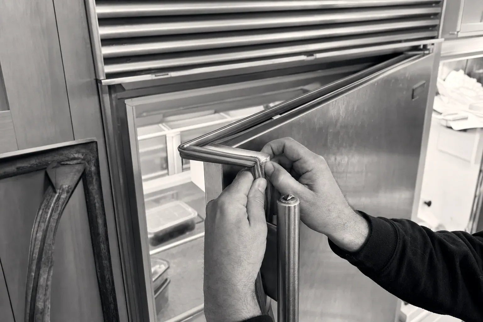 Hands fitting a new door gasket into the corner channel of a refrigerator door