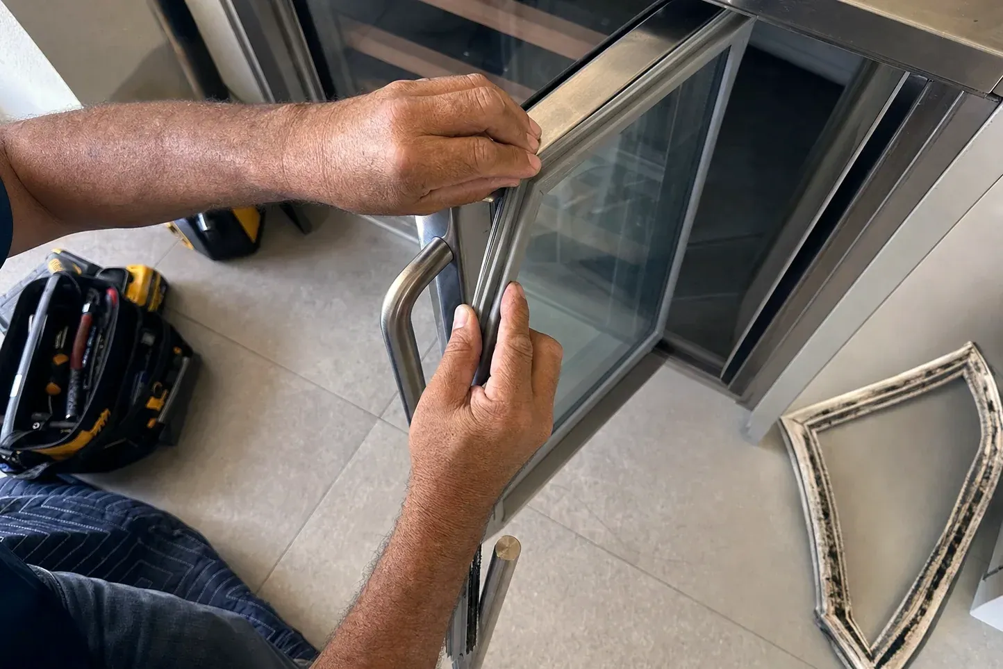 Hands fitting a gasket on a glass door, old gasket on floor