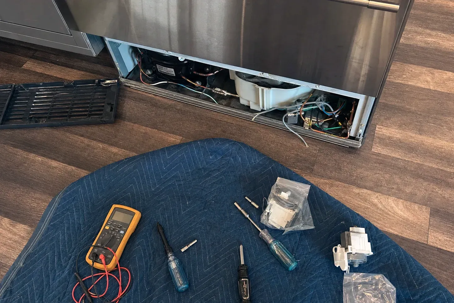 Overhead flat-lay of multimeter, screwdrivers, nut drivers and bagged replacement valves