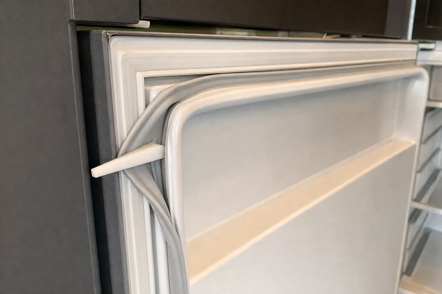Close-up of a refrigerator door gasket pulled away from the door edge