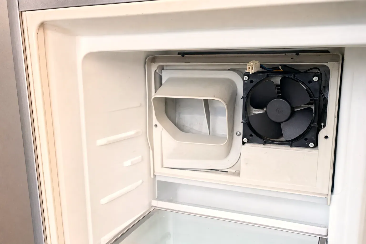 Freezer compartment with the evaporator cover removed showing the fan and air duct