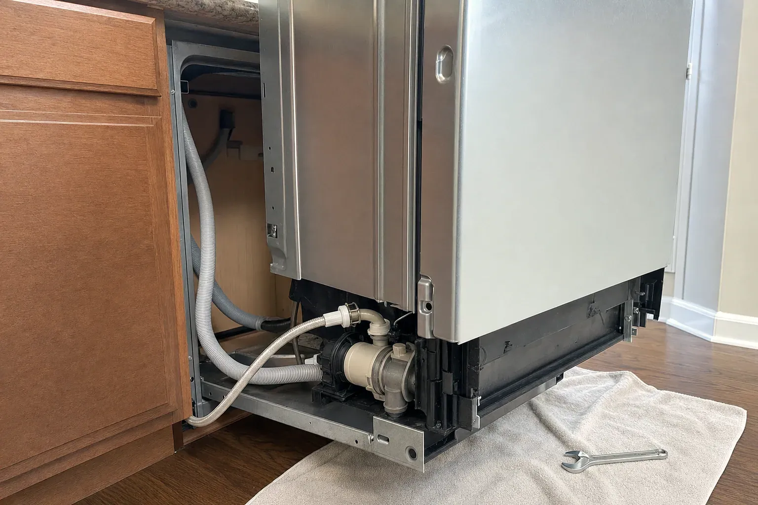 Dishwasher pulled out at an angle showing drain hose and pump housing