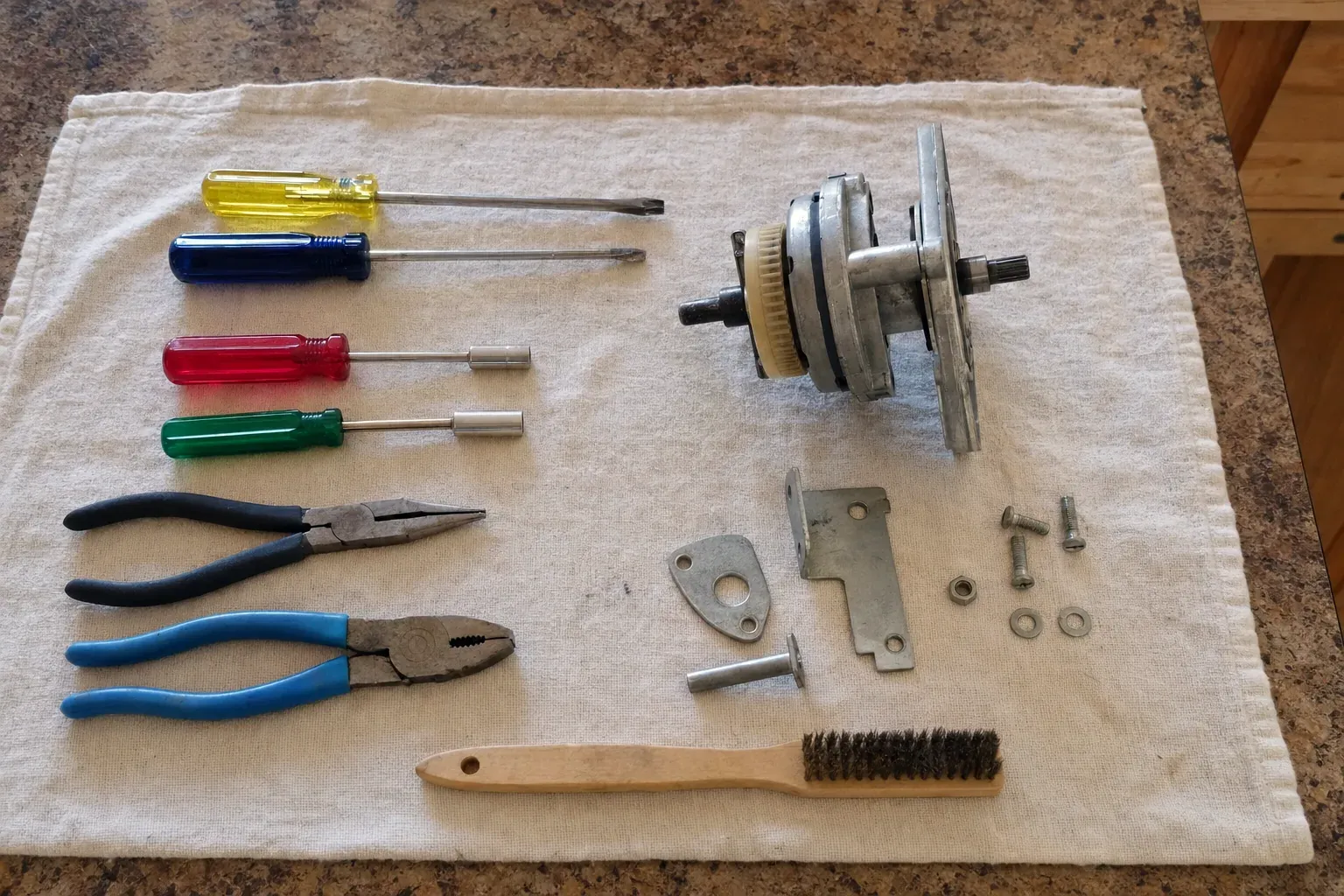 Disassembled motor or transmission part with screwdrivers and pliers on towel