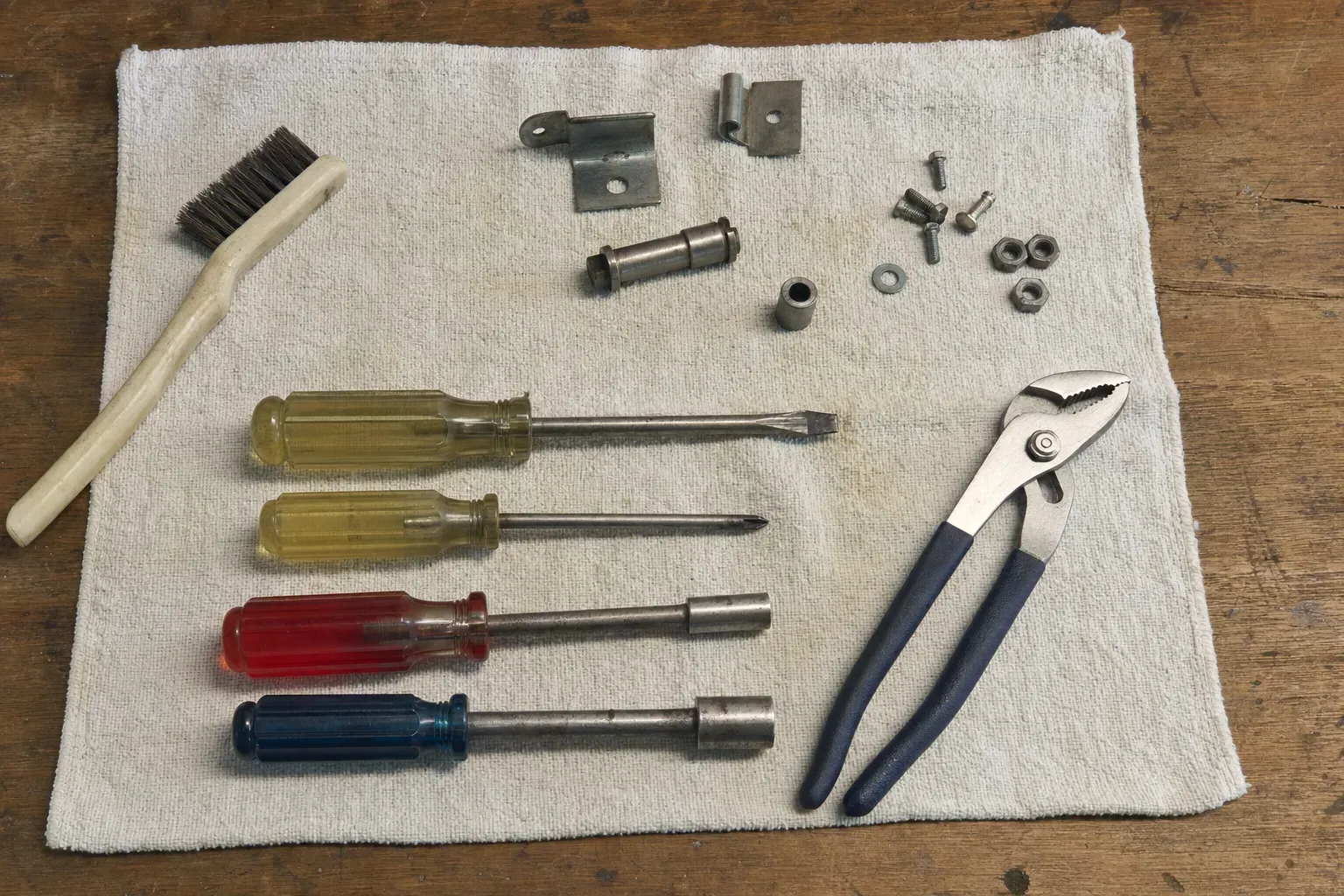 Pliers, four screwdrivers, brush, bolts and brackets on cloth