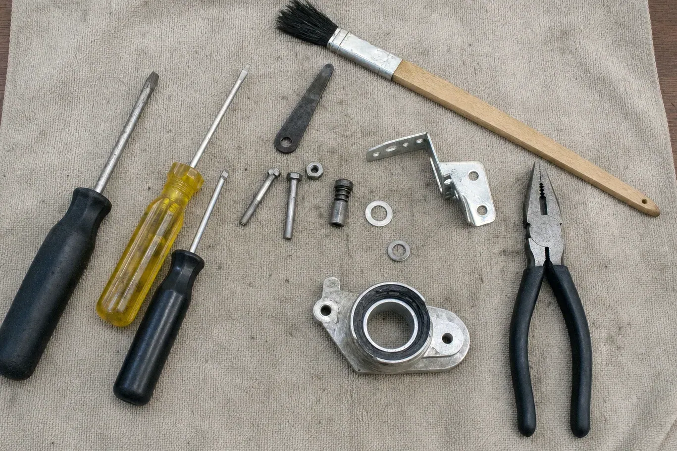Paintbrush, pliers, screwdrivers and hinge parts on canvas cloth