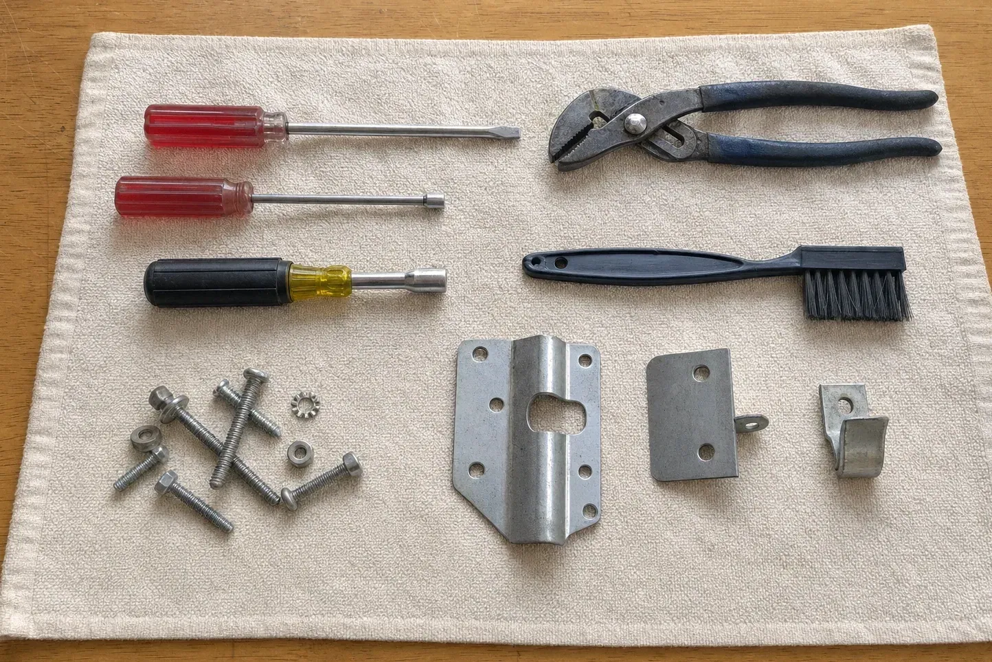 Slip-joint pliers, brush, screwdrivers, brackets and bolts on a towel