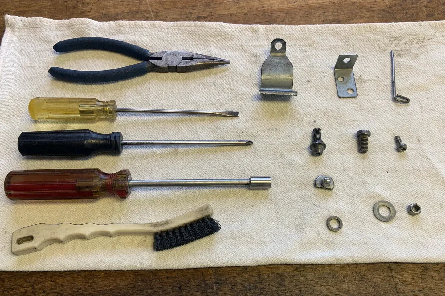 Brackets, screws, pliers, screwdrivers and a brush on white cloth