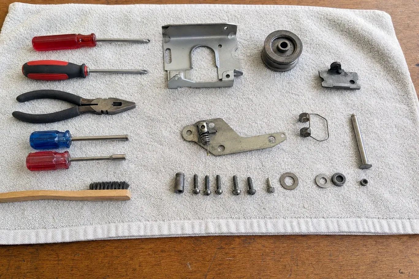 Pulley, springs, brackets, screws, screwdrivers and pliers on towel