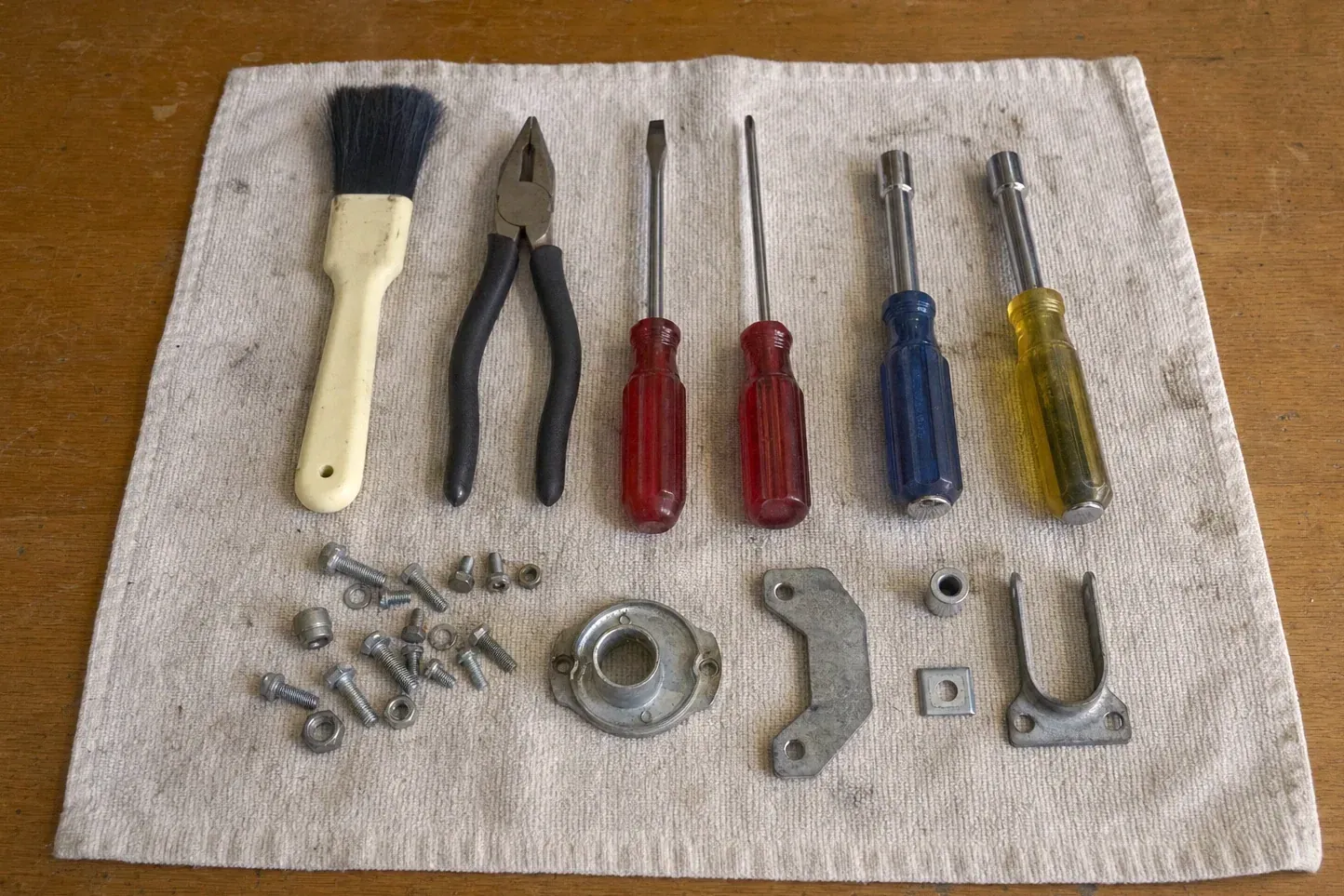 Nut drivers, pliers, paintbrush and metal parts on a rag