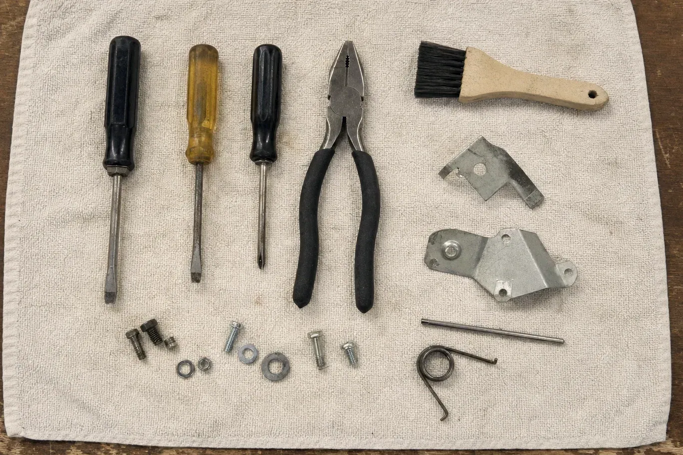 Brush, pliers, screwdrivers and metal brackets laid on cloth