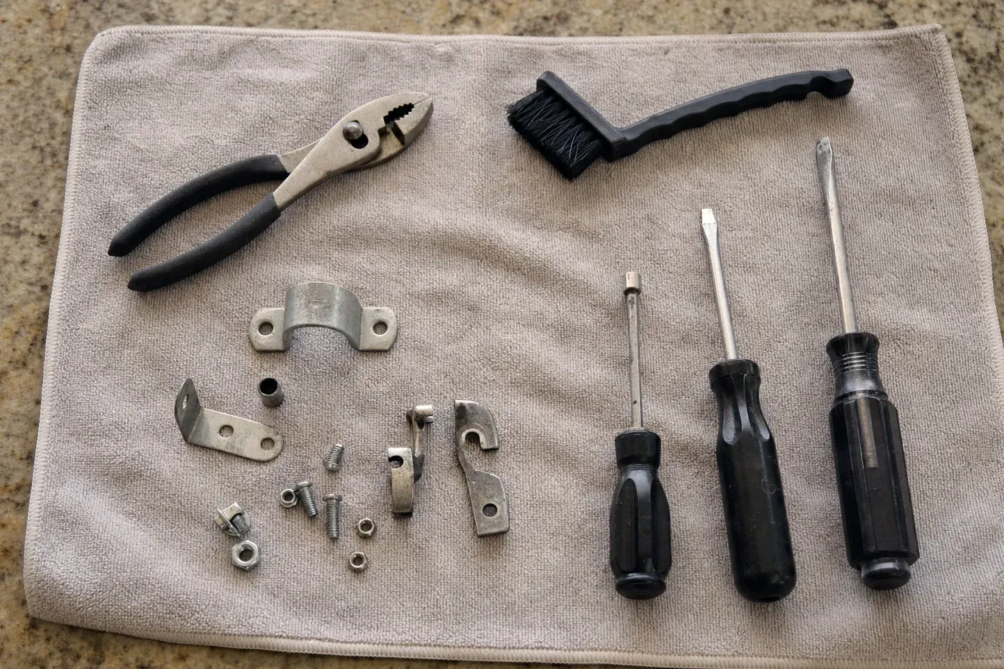 Brush, three black screwdrivers, pliers, clamp and small metal parts