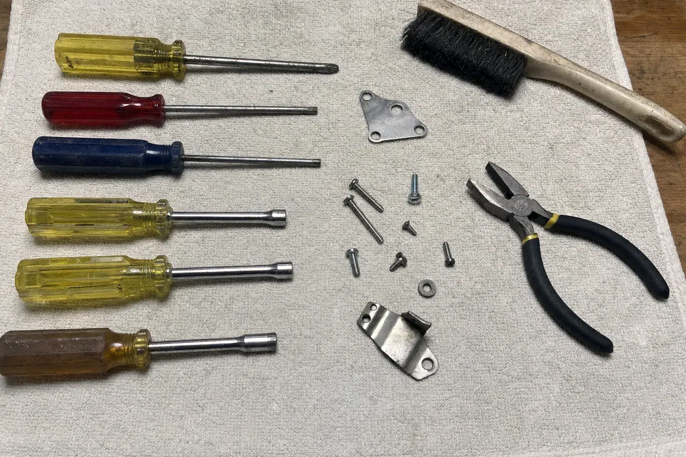 Row of screwdrivers, pliers, brush and loose screws on cloth